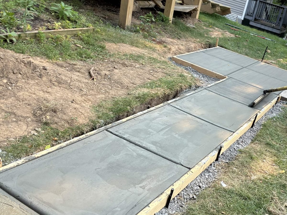 Fresh concrete walkway sections being finished inside wood forms